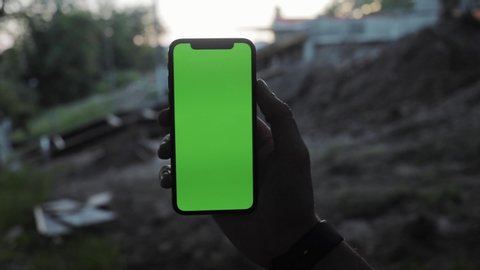 NEW YORK - April 19, 2019: Close up man hands using phone with vertical green screen smart mobile background 