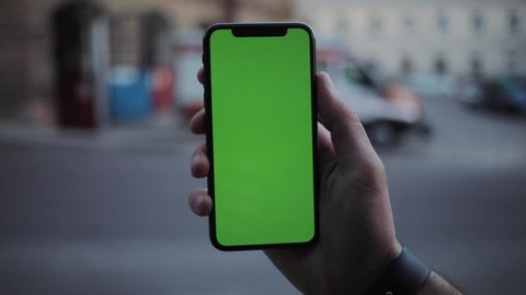 NEW YORK - April 5, 2018: Man hands using iphone with vertical green screen smart mobile background 
