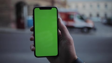 NEW YORK - April 5, 2018: Young man hands using iphone with vertical green screen smart mobile background 