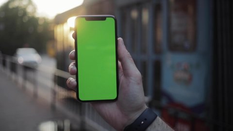 NEW YORK - April 5, 2018: Slow motion man hand using iphone with vertical green screen smart mobile view blurred background 