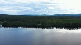4K Video of a Isolated House in the middle of a Forrest in Sweden. The Drone Gets Closer and Closer to the house. The Calm Water Mirrors the Pine Trees.