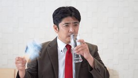 Asian man drinking a glass of water.