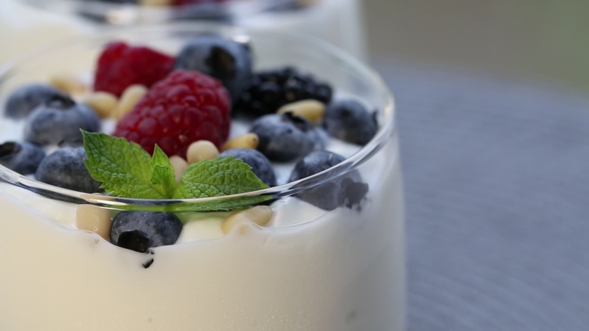 Two glasses of yogurt with berries, macro. Movement right and left