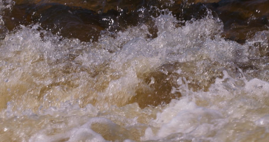 Extreme close up of raging water in rapids in slow motion.