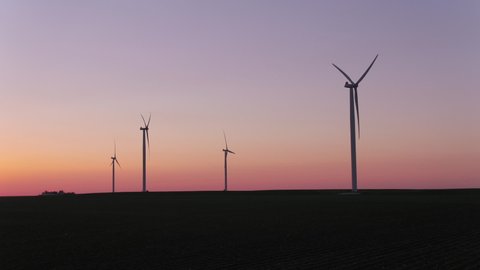 Zoom in on wind turbine silhouettes at sunset