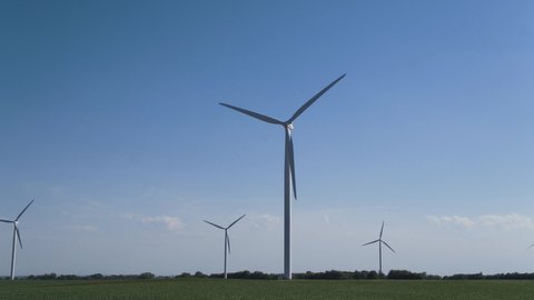 Panning shot of wind turbines in field