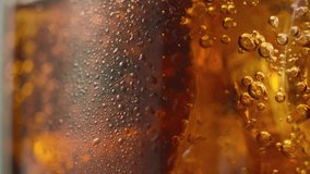 Macro shot of bubbles in glass with refreshing cola with ice. Video in slow motion.