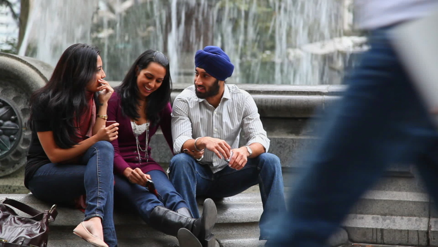 Friends sitting and talking at fountain in park