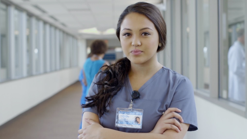 Serious nurse posing in hospital corridor then smiling | Shutterstock HD Video #1033065059