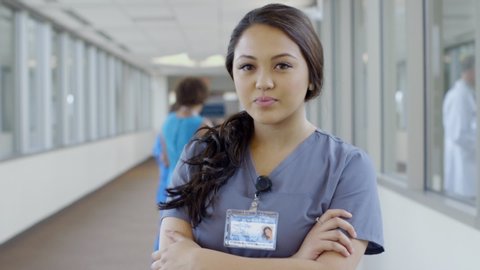 Serious nurse posing in hospital corridor then smiling