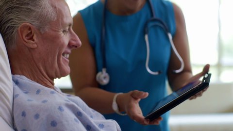 Doctor with digital tablet talking with patient in hospital bed