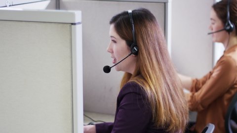 Businesswomen talking on headsets in call center cubicles