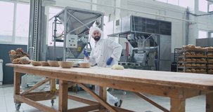 Large video taking of big manufacturing bakery dancing funny baker man with beard while preparing the dough for baking bread