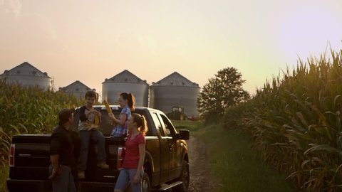Caucasian family on pickup truck playing with fresh corn