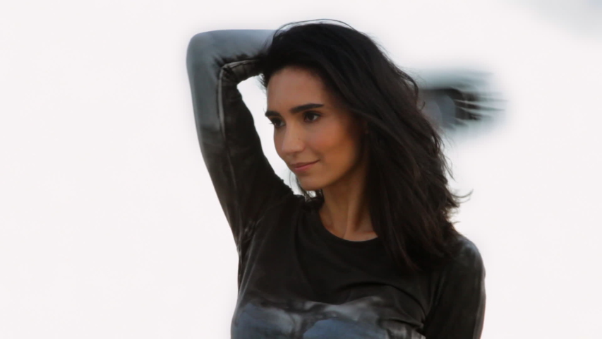 Hispanic woman standing under flock of birds near ocean