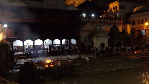 PASHUPATINATH TEMPLE, KATHMANDU, NEPAL - SEPTEMBER 2018: Hindus gather at Pashupatinath Temple complex for a nightly religious ceremony to wash away their deceased relatives' sins and cremate them.