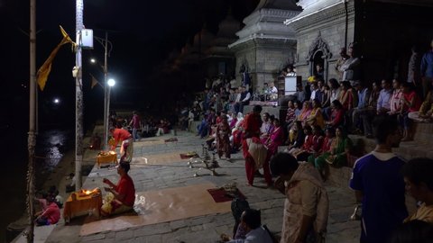 PASHUPATINATH TEMPLE, KATHMANDU, NEPAL - SEPTEMBER 2018: Scenic view of Pashupatinath Temple at night during a hindu cremation ceremony. Worshippers gather by the Bagmati river for air burial rituals.