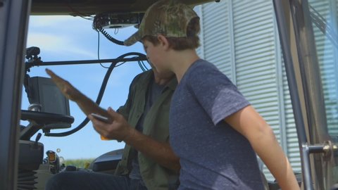 Caucasian father teaching son to drive tractor