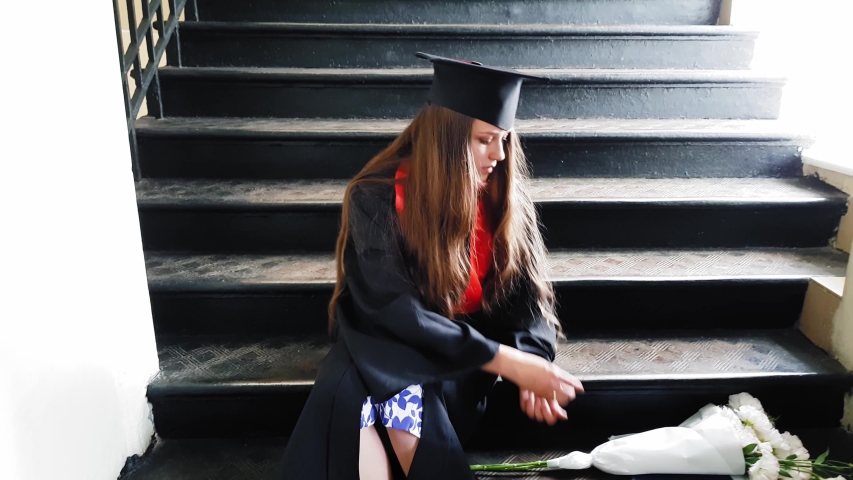 Beautiful student graduate master tapes her leg with a plaster while sitting on metal steps at the university