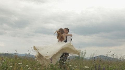 The groom runs for the bride on a mountain hills. Wedding couple. Happy family. Man and woman in love. Lovely groom and bride. Wedding day. Slow motion