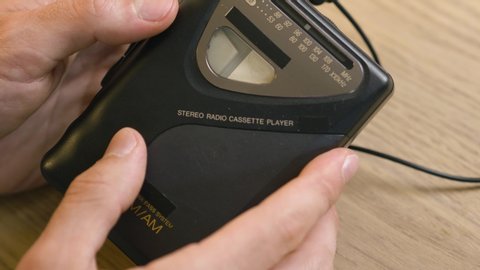 Using a portable cassette player by inserting a tape to listen to music.