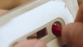 Rewinding a cassette tape with a pencil manually.