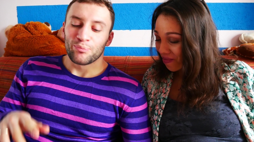 Young couple feeding each other with ice cream, sitting on the sofa