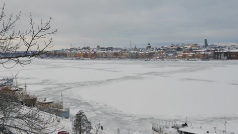 Right to left pan over frozen river of Stockholm to the city center during winter