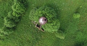 4K aerial summer morning high quality video footage of old unused rusty metal water pressure tower among lush green vegetation in Yaroslavl Oblast in central Russia