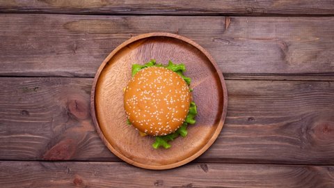Stop motion of eating a hamburger. It appears o the plate, then someone eats it. Modern unhealthy fast food eating. No people in frame. 4k.