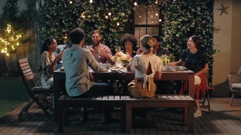 group of friends celebrating making toast to friendship at evening dinner party celebration drinking wine sharing homemade meal enjoying weekend reunion relaxing on calm summer night outdoors 4k