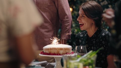 friends celebrating birthday party dinner surprising friend with cake happy woman laughing blowing sparklers enjoying fun evening celebration on beautiful summer night at home 4k