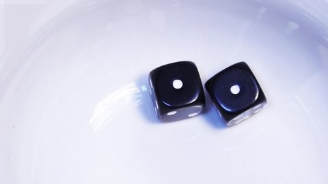 Two black dice bounce and rebound in slow motion on a white background before resting at double one, a score of two, sometimes called "snake eyes" or a "loose deuce".