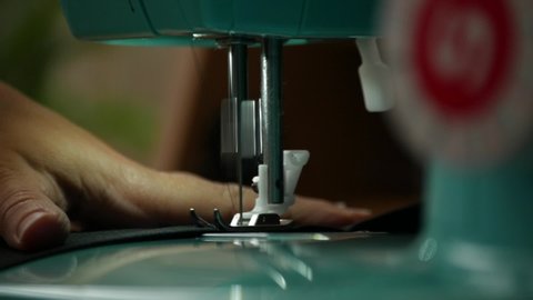 A female hand pushes material through a sewing machine