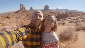 Couple traveling in USA take selfie picture at Monument Valley in Utah state; people adventure travel concept; boyfriend and girlfriend having fun on road trip vacations discovering nature 