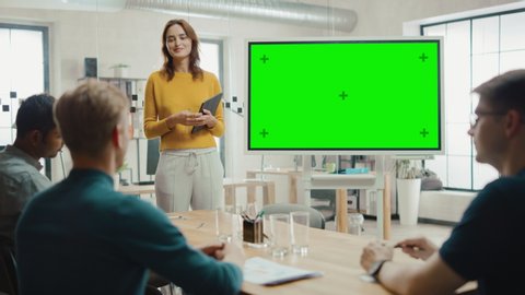 Female Project Manager Holds Meeting Presentation for a Team of Developers. She Shows Green Screen Interactive Whiteboard Device for Business Planning Concept. Young People Work in Creative Office
