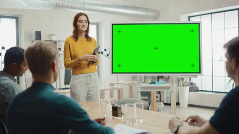 Female Project Manager Holds Meeting Presentation for a Team of Developers. She Shows Green Screen Interactive Whiteboard Device for Business Planning Concept. Young People Work in Creative Office