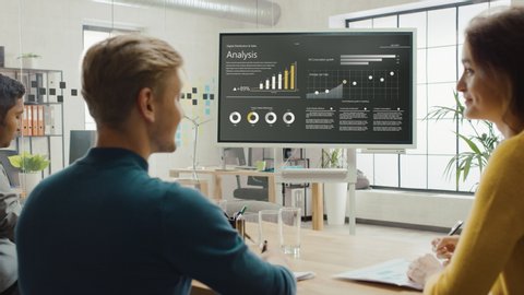 Team of Analytics, Economists and Young Businesspeople Hold Meeting Presentation use Shows Digital Interactive Whiteboard with Growth Analysis, Charts, Statistics and Data. People Work in Office
