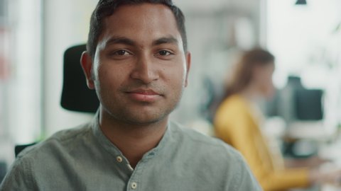 Portrait of Handsome Professional Indian Man Working at His Desk, Looking at the Camera. Successful Man Working in Bright Diverse Office