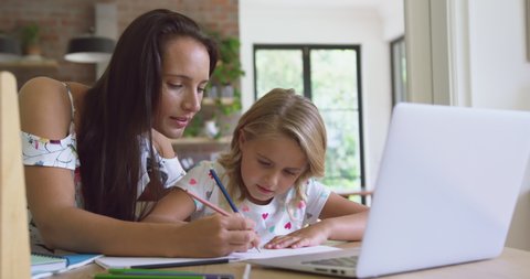 Caucasian mother helping her daughter with homework in a comfortable home 4k. Social distancing and self isolation in quarantine lockdown for Coronavirus Covid19