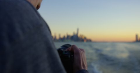 Handsome Man Photographing Sunset On Hudson River whilst Moving Away From Iconic New York Skyline And Impressive Skyscrapers at Sunset