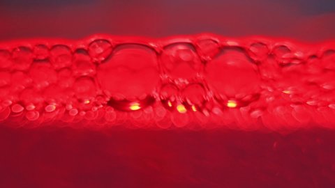 Close Up Of Exploding Red Air Bubbles In A Purple Liquid.
