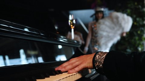 Theme party - A man playing piano - A woman in glisten clothes pick up a glass of champagne Adlı Stok Video