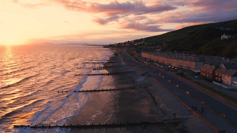 Drone flight in dramatic sunset light over scenic coastal town in Barmouth, North Wales, UK Video de stock