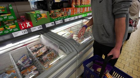 Stoke on Trent, Staffordshire / United Kingdom (UK) - 01 23 2019: A young man puts some chicken Kievs into his shopping basket at the Lidl supermarket, store, shop in the town centre