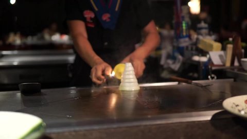 Hibachi chef is giving a fire show at a Japanese restaurant