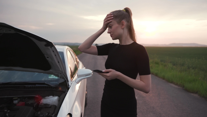 Nervous young woman stand use phone at sunshine looking at engine of breakdown car at the field alone automobile girl help lost road trouble upset side transportation travel close up slow motion Royalty-Free Stock Footage #1033142195