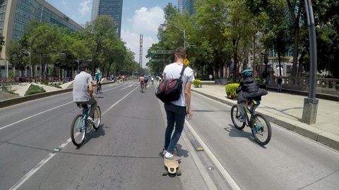 Mexico City, Mexico-June 2019: Young man on a skateboard riding with cyclists, in recent years, Mexican society has opted for the bicycle and skateboard as sustainable means of transport.