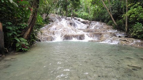 A beautiful low vantage point view of the cascading waterfalls at Dunn's river falls with lush vegetation with water splashing in Ocho Rios on tropical island of Jamaica a popular travel destination.