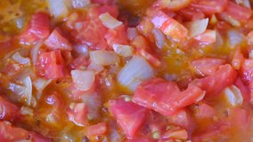 White onion chopped into small pieces stewed with red fresh tomatoes with olive oil on a non-stick griddle, video clip close-up shooting